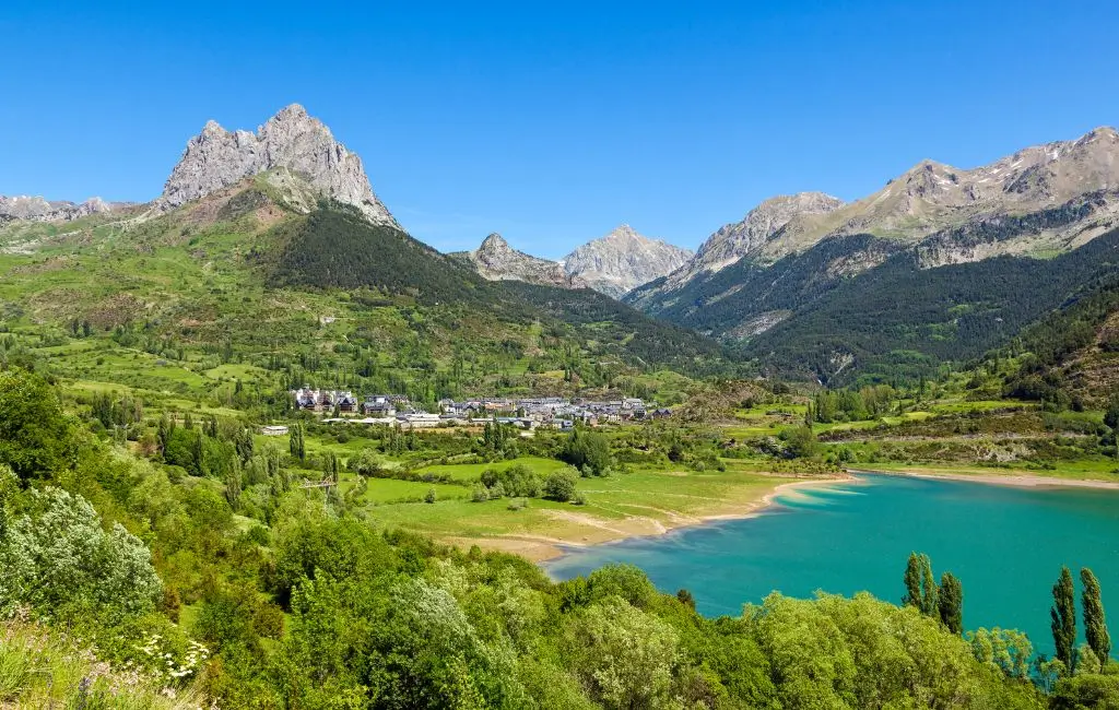Valle verde con lago e villaggio nei Pirenei dell’Aragona, Spagna, lungo un itinerario 4x4