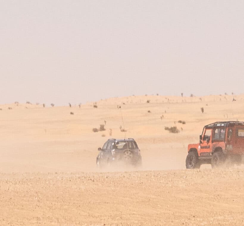 Veicoli 4x4 in movimento nel deserto tunisino con nuvole di polvere durante il viaggio Capodanno Wild Sahara AF Travel Firenze