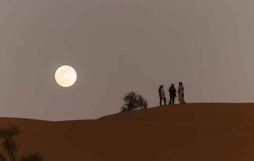 Persone sulle dune del Sahara illuminate dalla luna durante il viaggio Wild Sahara AF Travel Firenze